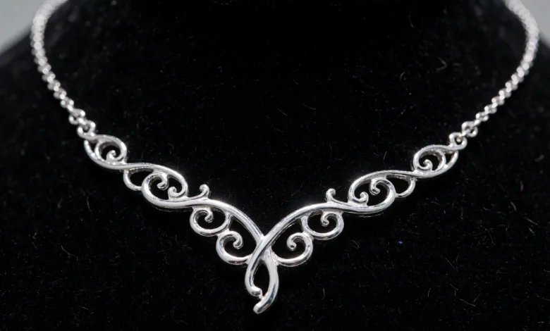 A close-up of an elegant platinum jewelry piece, such as a delicate necklace with intricate filigree design, resting on a soft black velvet background, highlighting the metal's bright white luster, durability, and rarity, with subtle light reflections emphasizing its purity and sophistication in fine jewelry art